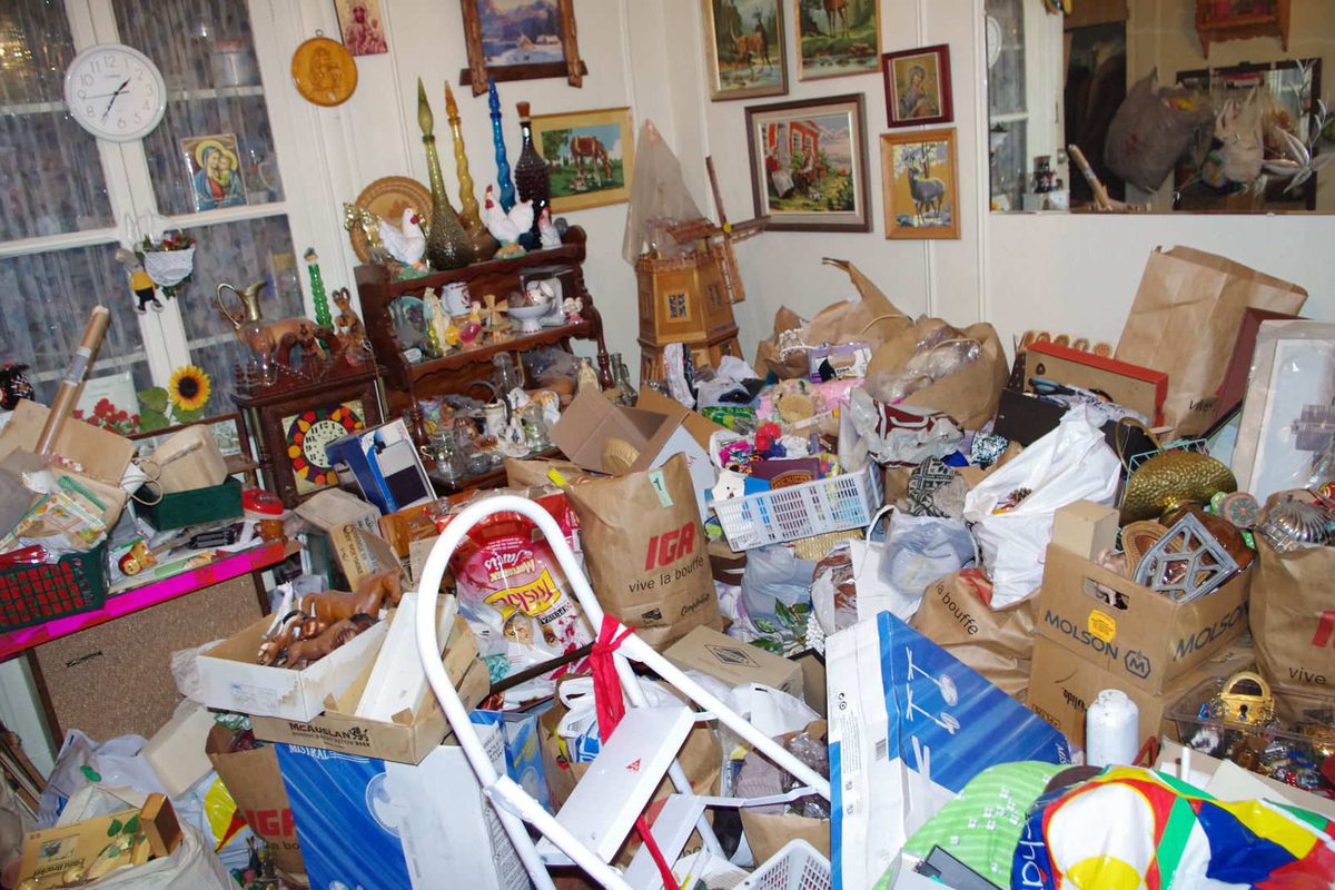 Salon entièrement encombré de sacs, de cartons et d'objets accumulés jusqu'à hauteur des meubles