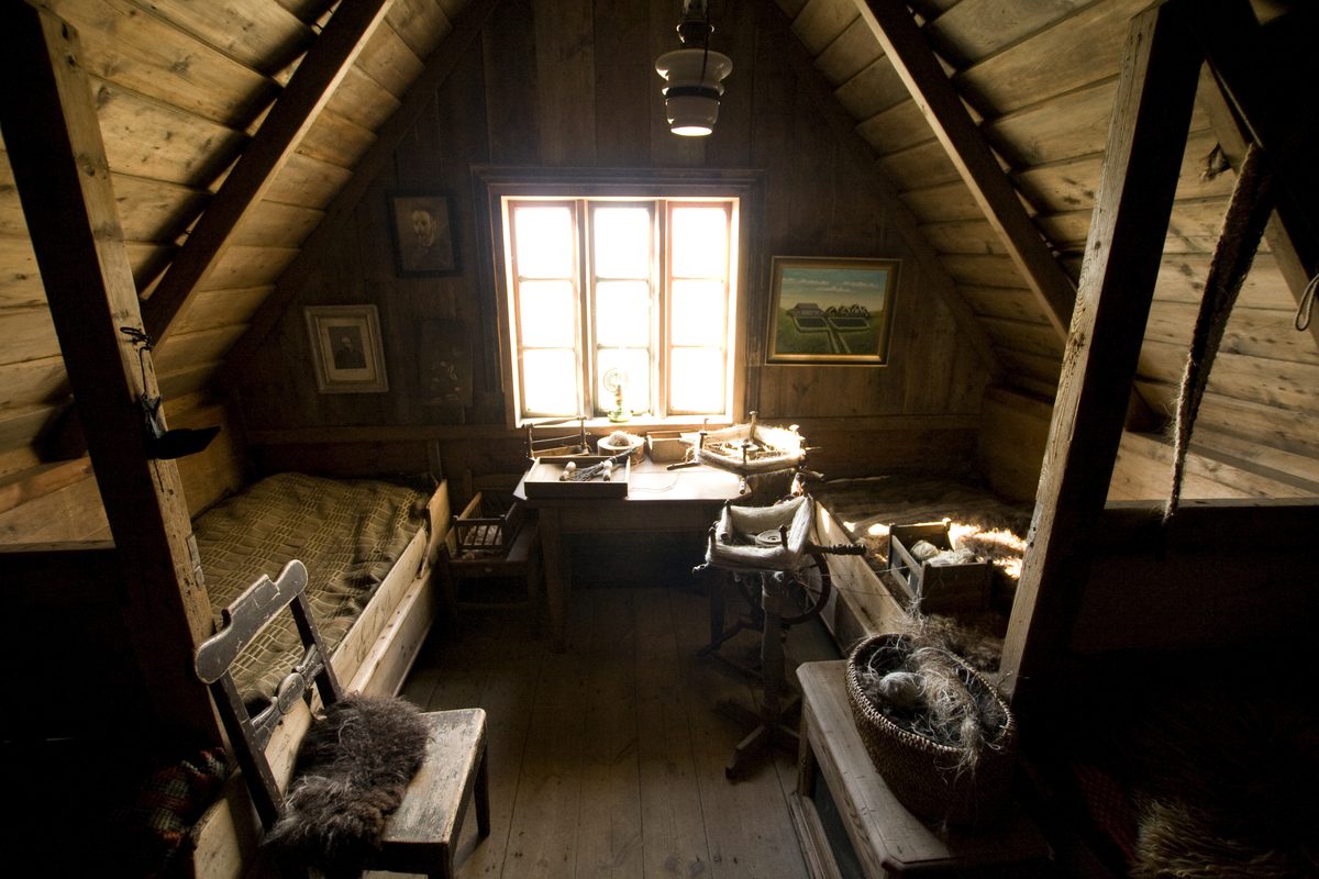 Grenier aménagé sous combles avec poutres en bois apparentes et mobilier ancien