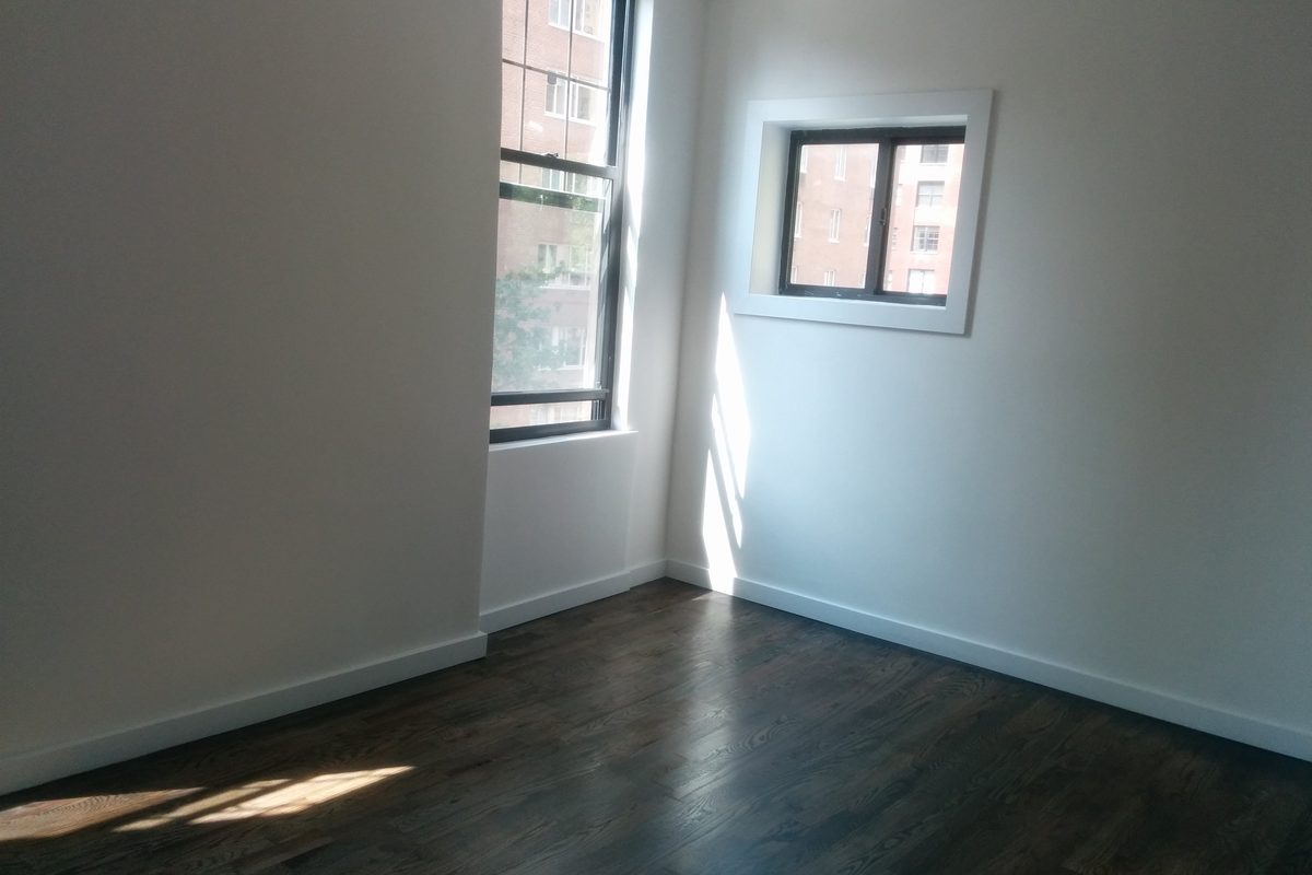 Pièce d'appartement entièrement vidée, parquet sombre et murs blancs, prête pour la remise des clés