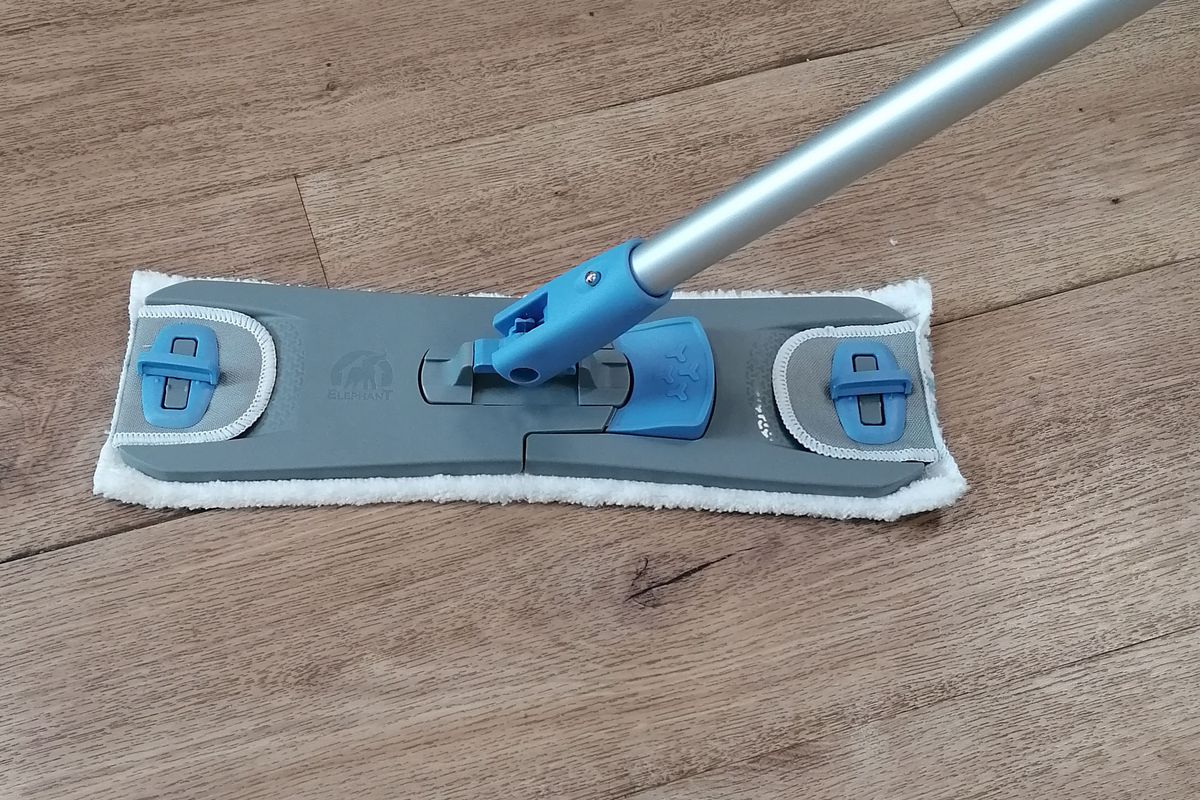 Balai à plat en microfibre posé sur un parquet en bois, matériel de nettoyage des sols